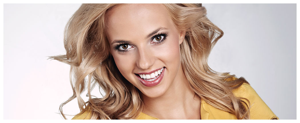 Smiling woman with blonde hair, yellow top.