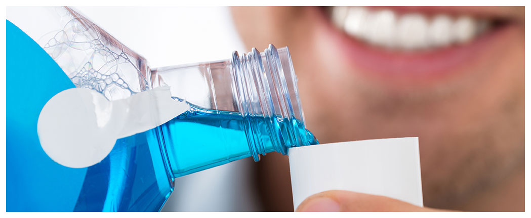 Pouring blue mouthwash into a cap.