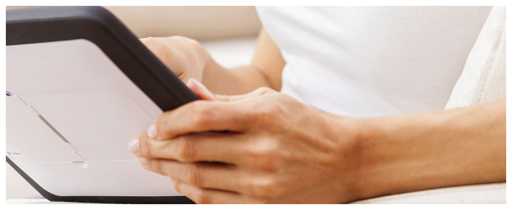 Person holding a tablet while sitting.