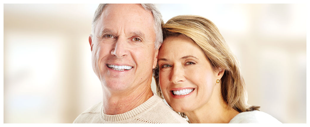 Smiling older couple embracing, bright background.